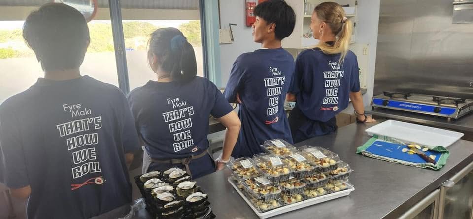 Four of the Oyster Barn team in their Eyre Maki shirts, packing trays of sushi at the bench