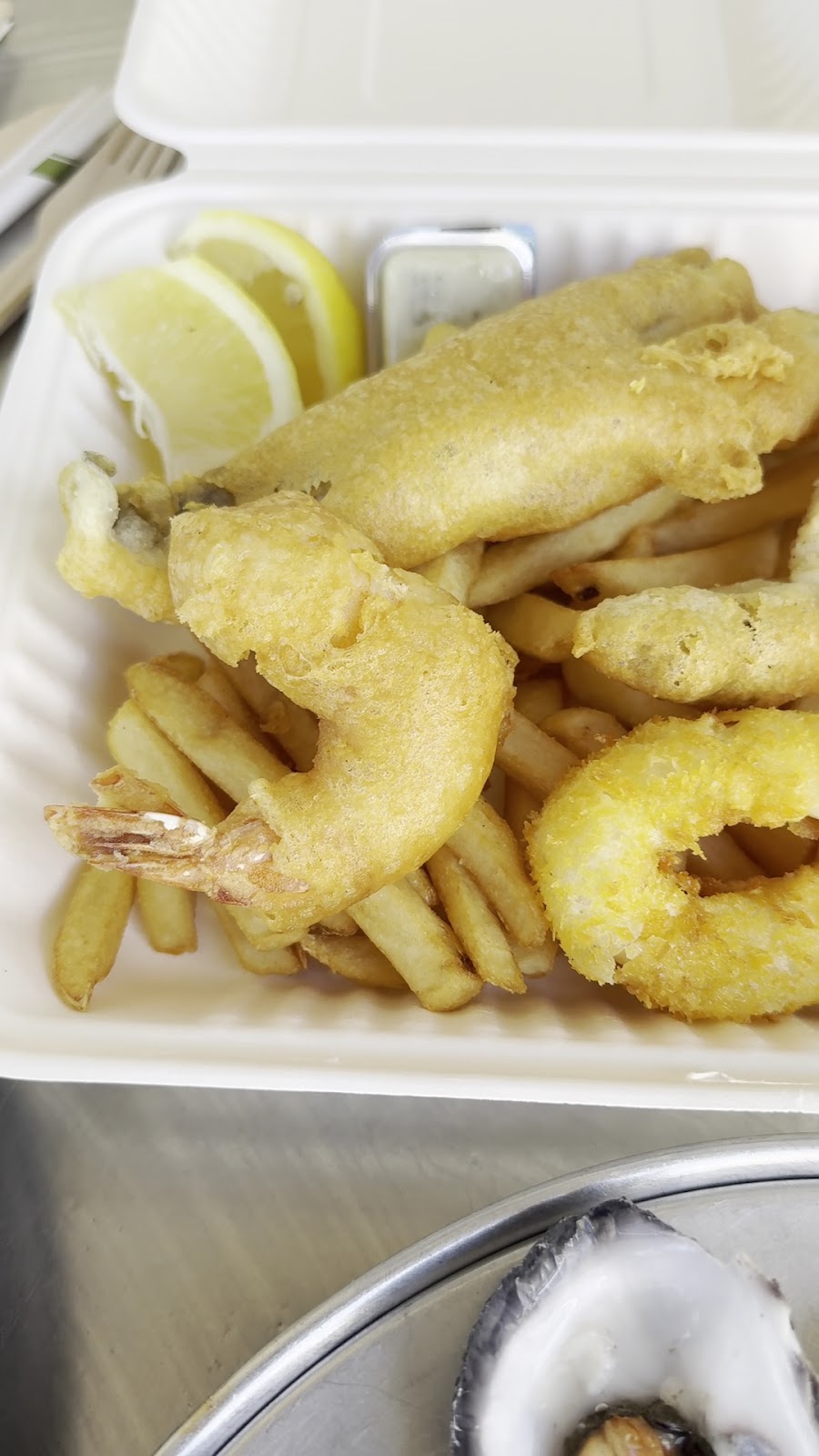 A box of fish and chips with a battered prawn and a crumbed squid ring