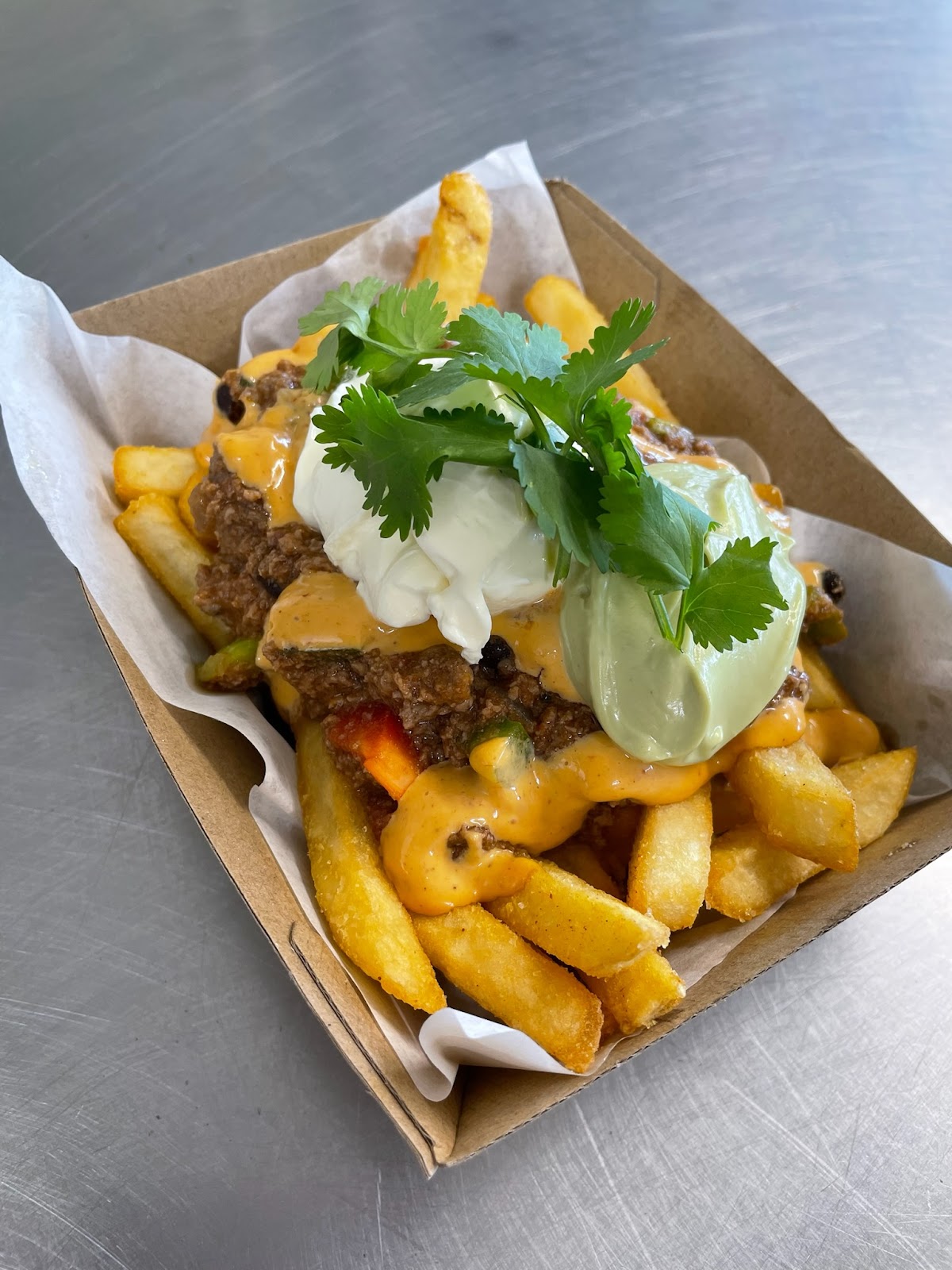 Loaded chips with chilli beef, sour cream, avocado cream and coriander