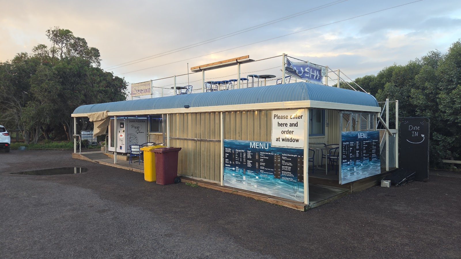 The barn at dusk, menu boards lit and the dine in board out the front